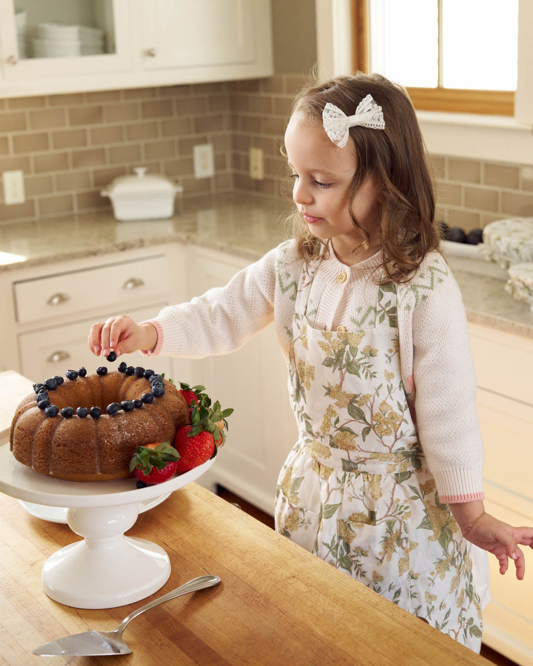 Kids cotton apron in hand-drawn floral print with adjustable ties, ideal for cooking and imaginative play.