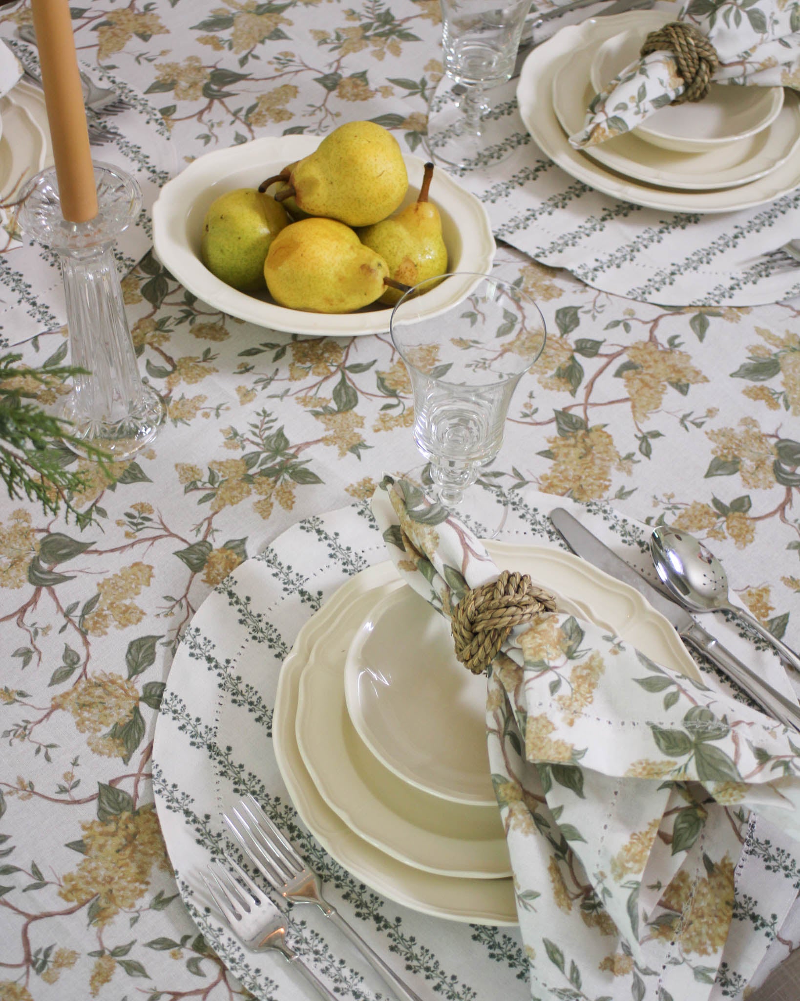 Hyacinth Marigold floral tablecloth draped naturally on a dining table, layered with coordinating linens
