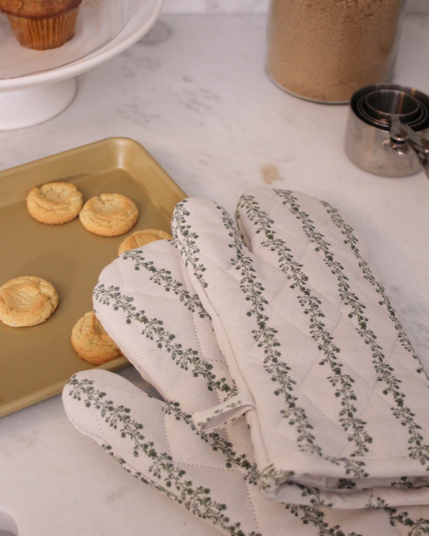 Begonia oven mitts on counter next to freshly baked Christmas cookies 