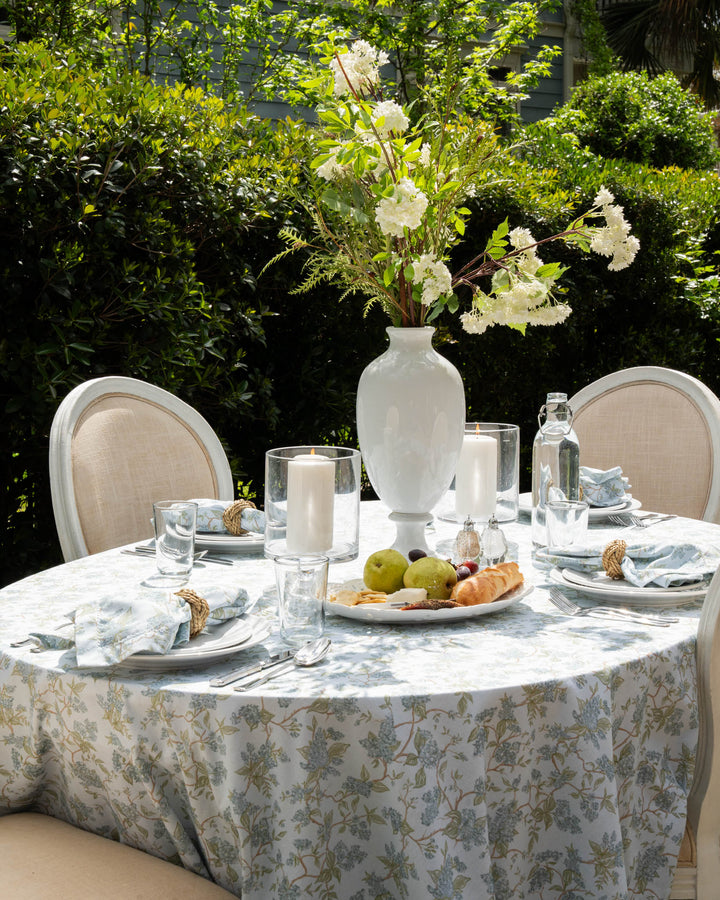 Blue and green chinoiserie floral wedding tablecloth made from 100% cotton, featuring a delicate botanical vine print inspired by English country gardens. This rectangle cotton tablecloth is ideal for wedding welcome tables, rehearsal dinners, Easter table decor, or Mother’s Day brunch. Designed in Charleston and ethically made in India using non-toxic dyes, it complements grand millennial, French country, farmhouse, and garden party table settings.