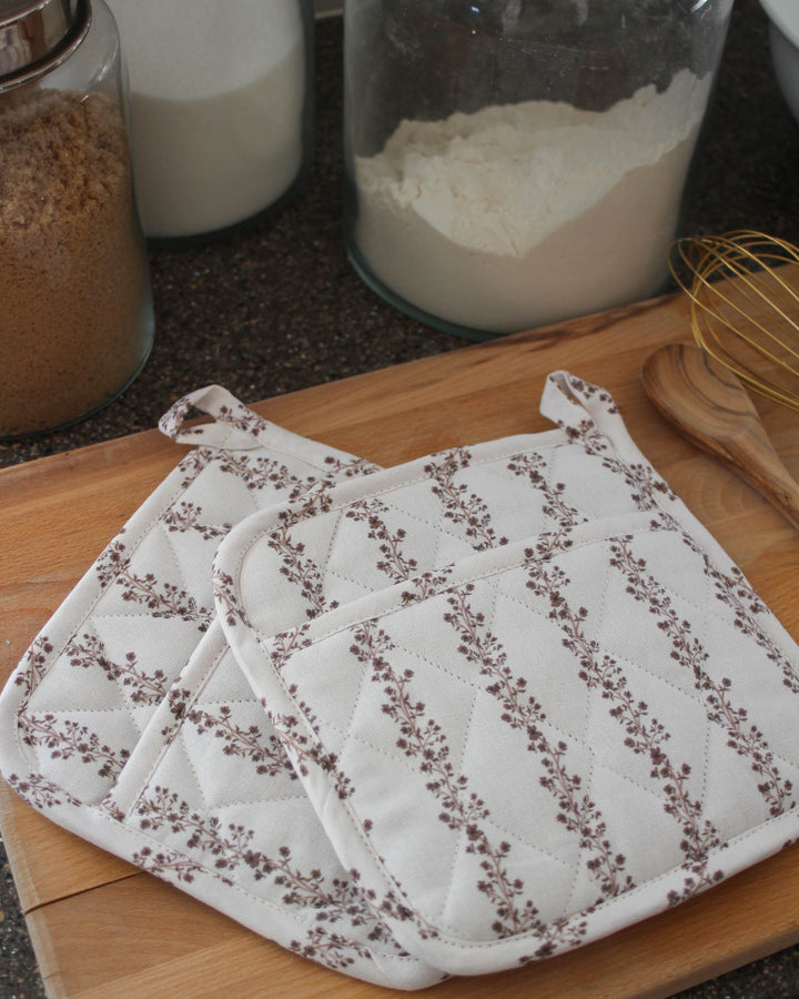 Beautifully crafted chestnut brown floral stripe quilted cotton woven potholder set. This set of 2 pot holders is made from premium cotton with recycled cotton insulation, making them perfect quilted potholders for baking and cooking. Each 8 inch square pad includes a hanging loop. Ideal as floral hot pads or quilted trivets for protecting surfaces. These spring kitchen essentials are a great gift for her, mom, or a grandma gift. Perfectly complements grand millennial decor style.