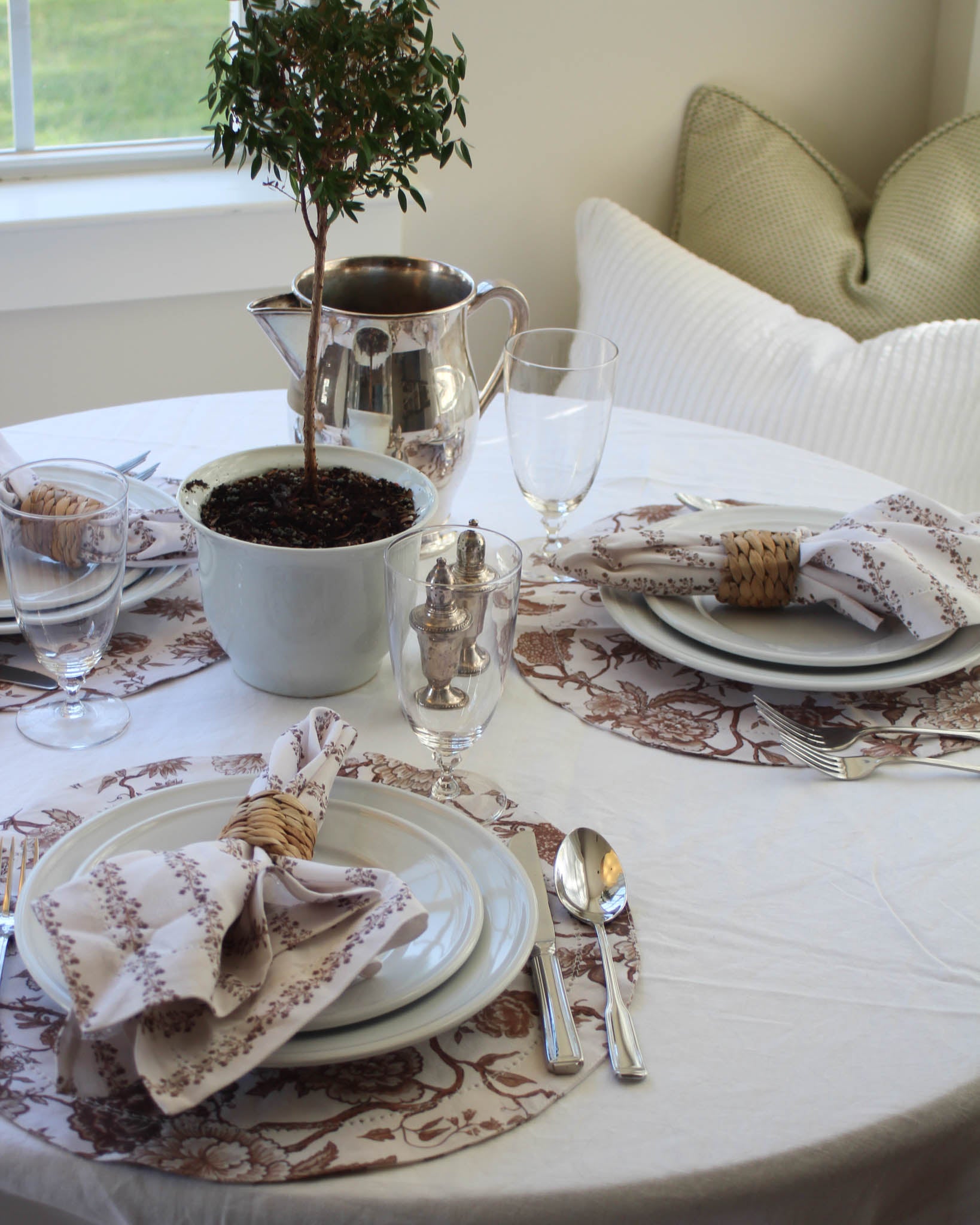 Set dining table with round floral placemats and brown floral napkins for fall.