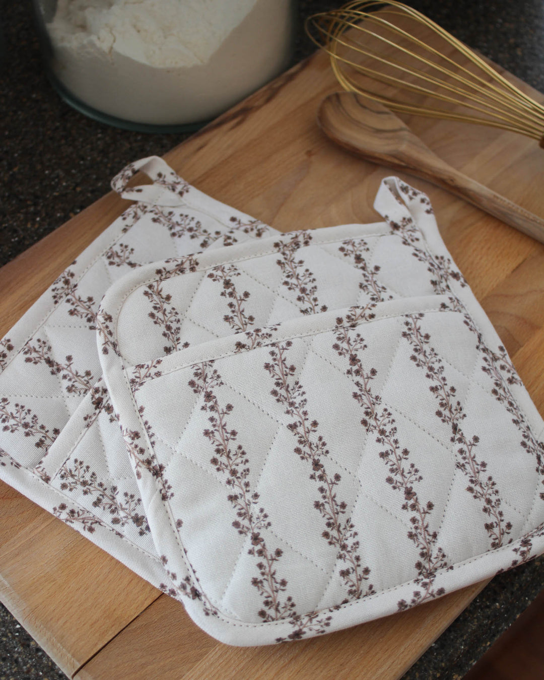 Heat-resistant cotton pot holders in floral stripe design, perfect for sourdough baking and serving dishes.