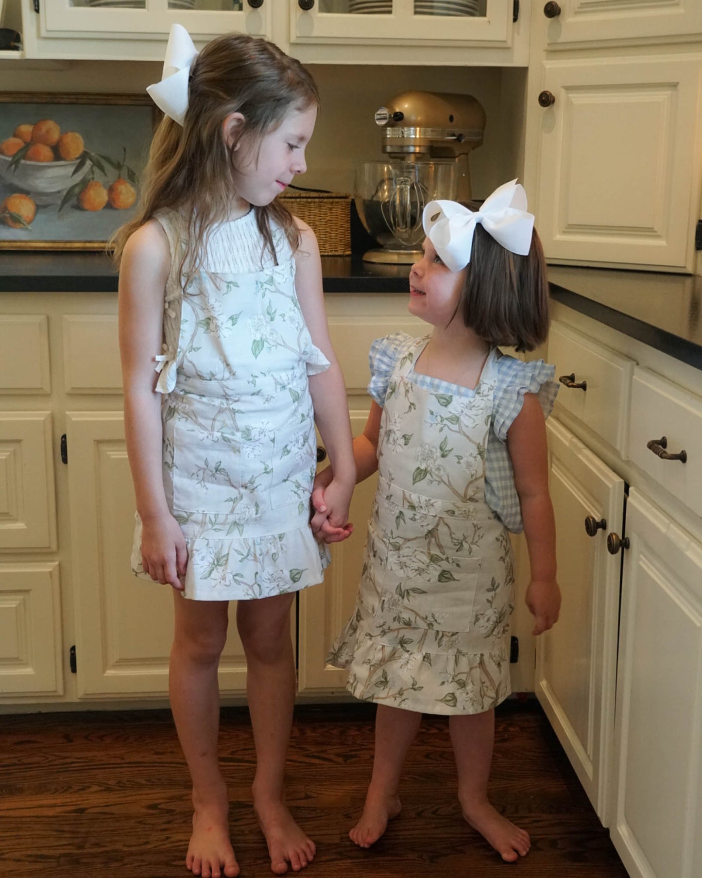 Little girl's Camellia apron featuring delicate ruffles and a charming floral pattern. Perfect for cooking, baking, and crafting.