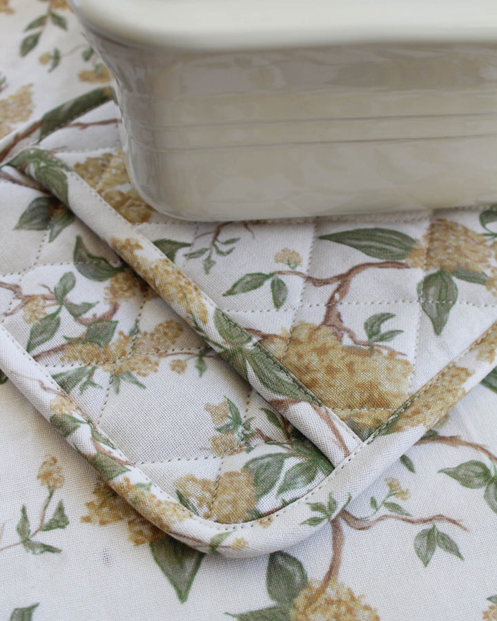 Classic grand millennial style yellow botanical potholders for the stylish home chef. This set of two quilted hot pads offers superior heat protection while handling hot cookware and sourdough pans. Made from durable cotton with a heritage-inspired floral design, each 8-inch square potholder is finished with a loop for hanging. Whether used as a trivet for a garden brunch or as daily hot pads, these yellow floral potholders add a sophisticated layer of sunshine to your kitchen space.