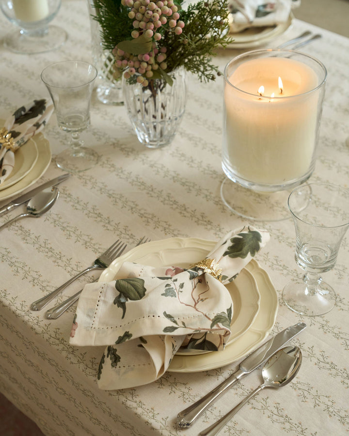 Neutral woodland dinner napkins featuring green foliage, oak leaves, and winter berries for Christmas tablescapes and seasonal entertaining.