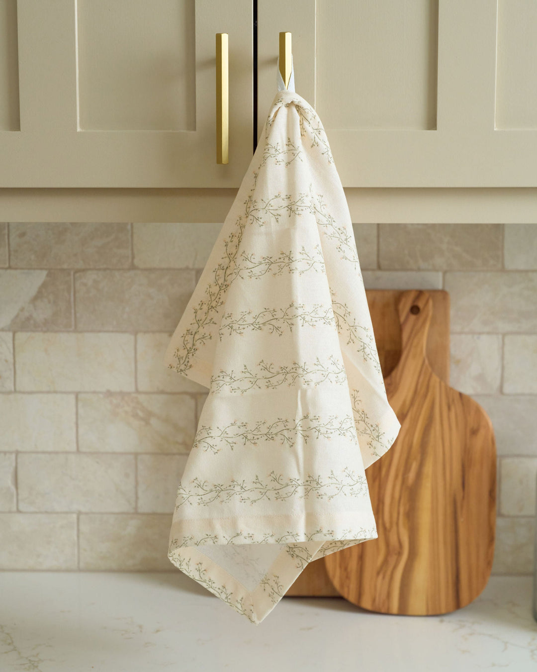 Cream floral stripe cotton tea towel featuring hand-drawn moss green and pale yellow botanicals, styled for everyday kitchens, spring brunches, summer hosting, fall cooking, Thanksgiving preparations, Christmas baking, holiday décor, hostess gifting, and year-round display.