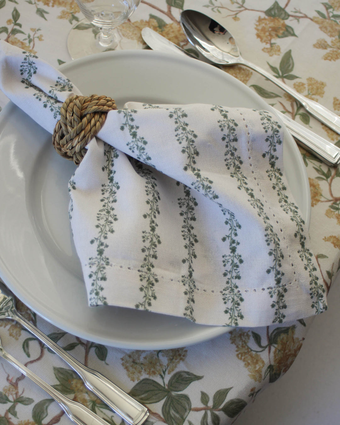 Spring floral stripe napkins in green styled for a holiday table with layered linens and fresh flowers.