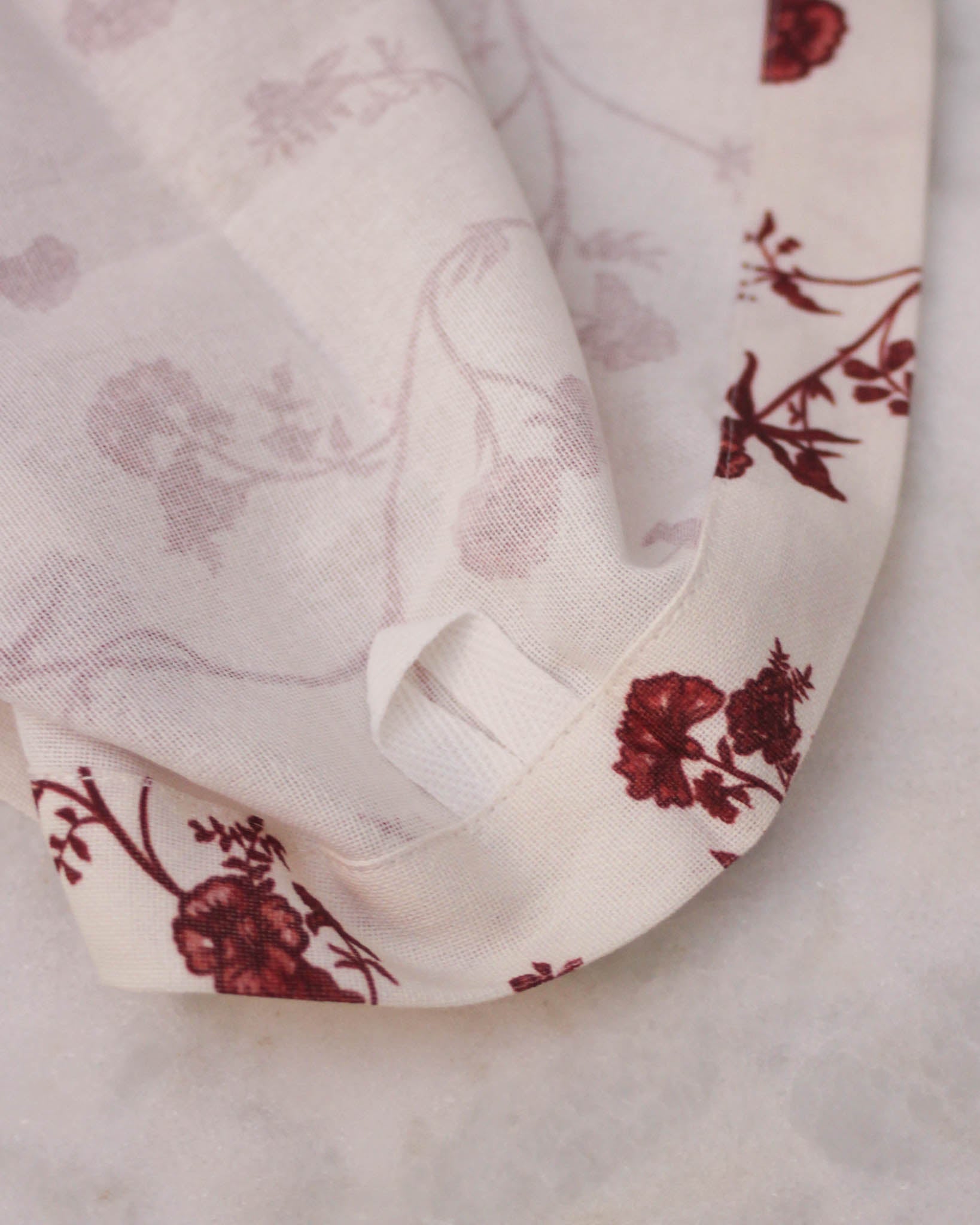 Elegant kitchen tea towel featuring red vine print and functional hanging loop for easy display.