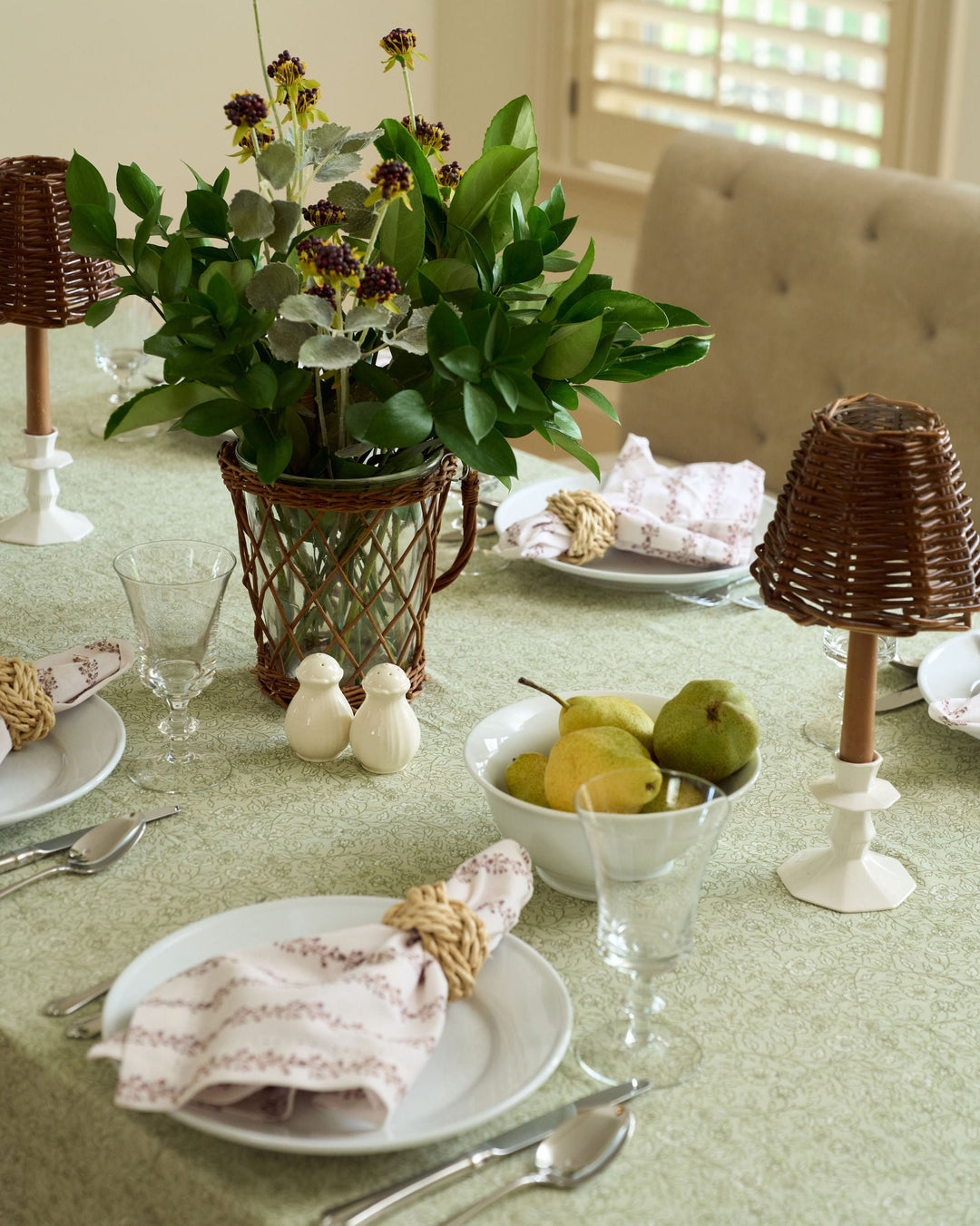 Brown and sage green Thanksgiving tablecloth with a neutral botanical floral print, styled with classic fall table linens and seasonal greenery.