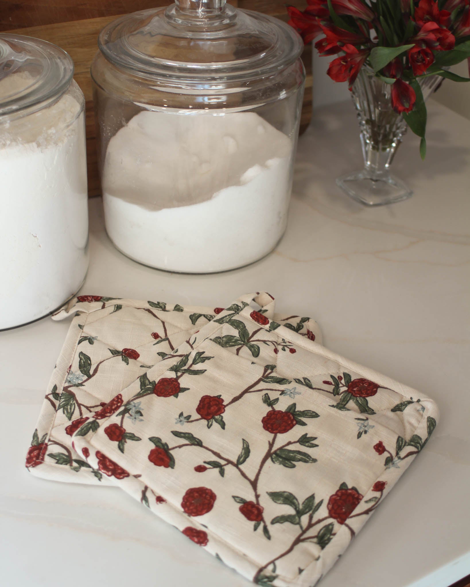 Exquisite red and green floral potholder (set of 2), designed to protect your hands from heat while adding a touch of charm to your kitchen décor. Handcrafted with love, each potholder is made from durable organic cotton, ensuring both style and sustainability. The inside is filled with heat-resistant recycled cotton, offering excellent insulation so you can confidently handle your hot pots and pans without worry. Out potholder measures 8" square