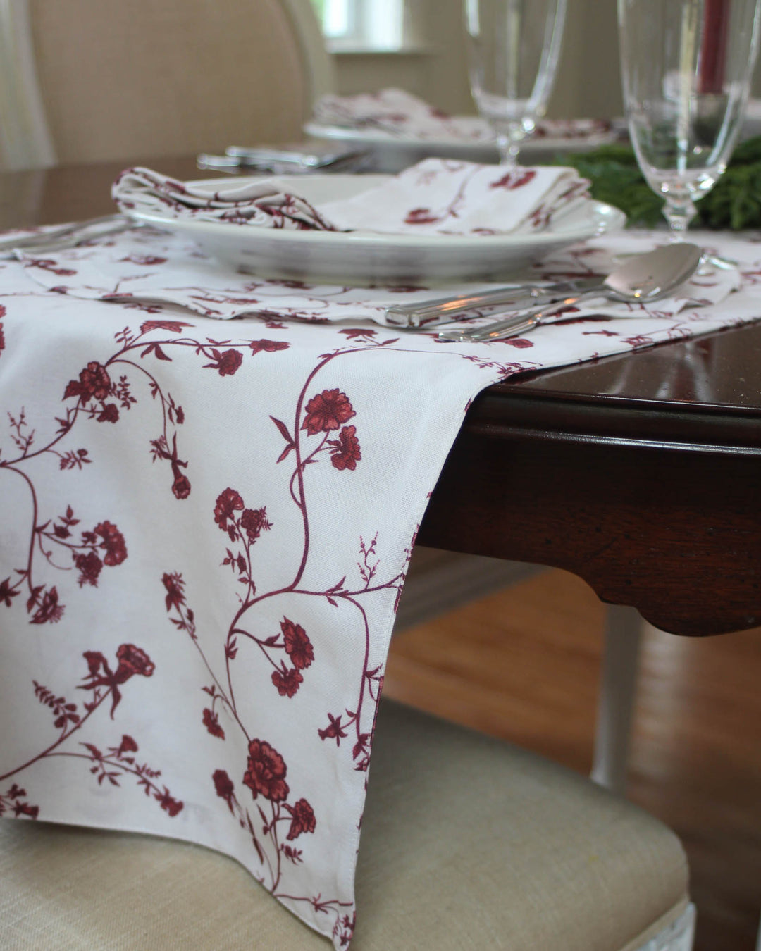Red floral farmhouse table runner made from 100% organic cotton. This hand-drawn botanical design features vibrant red blossoms and green leaves, perfect for bringing a hint of traditional color to your kitchen. A versatile piece for Easter table decor, spring hosting, or even an earthy Christmas table setting. The durable cotton is machine washable and gets softer over time. A beautiful way to add a pop of classic color and rustic elegance to your everyday family meals.