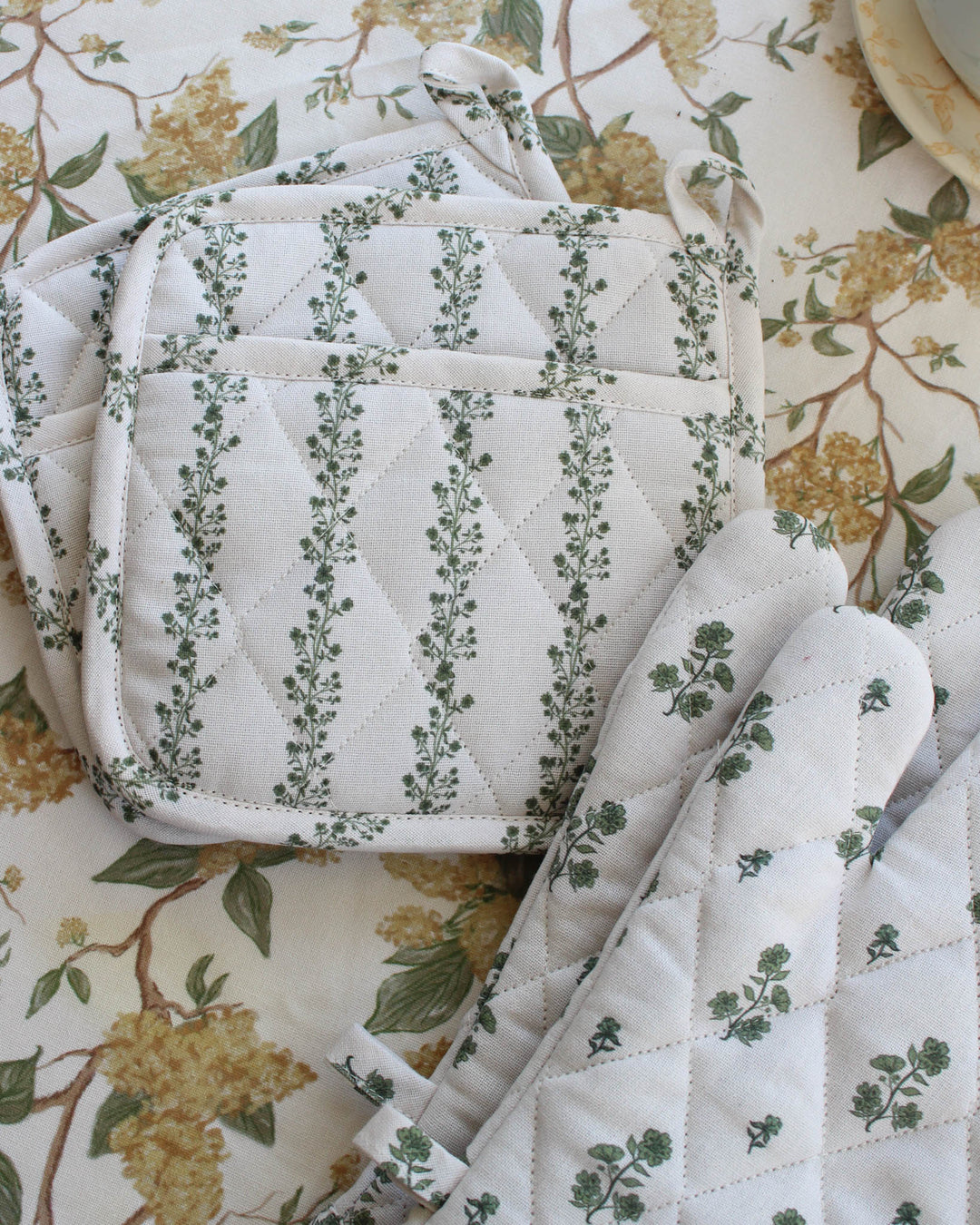 This green floral stripe quilted cotton potholder set of 2 brings functionality to your spring kitchen. Made of premium cotton with recycled insulation, these quilted hot pads are designed for safe handling of hot trays. Each 8x8 woven potholder includes a loop for hanging. Ideal as quilted trivets for a Mother's Day brunch or floral hot pads for Easter baking. A perfect gift for her, mom, or grandma, these country kitchen accessories embody grand millennial decor with a green print.