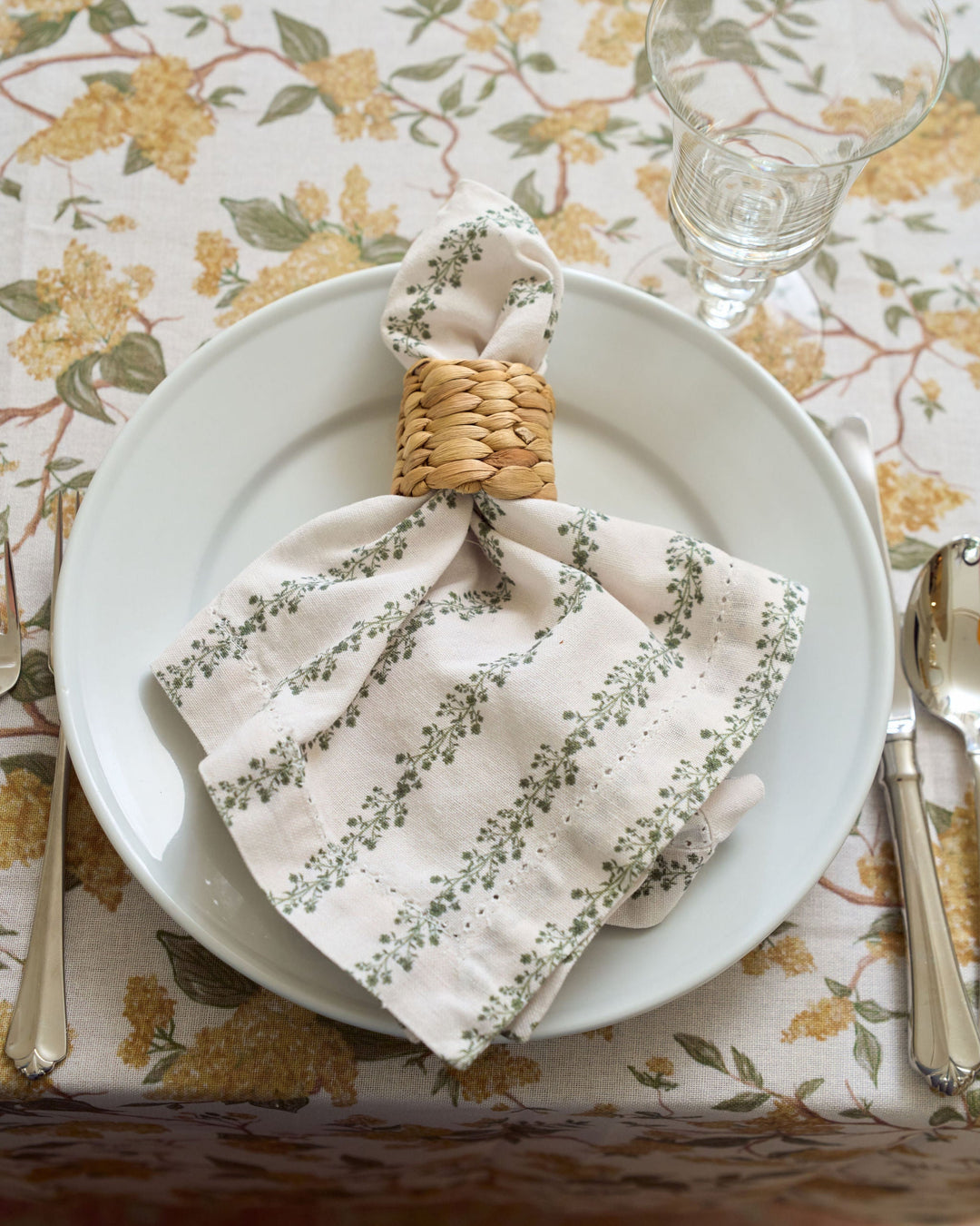 Set of four green floral stripe cotton napkins styled with classic dinnerware and coordinating linens for a layered, inviting table setting.