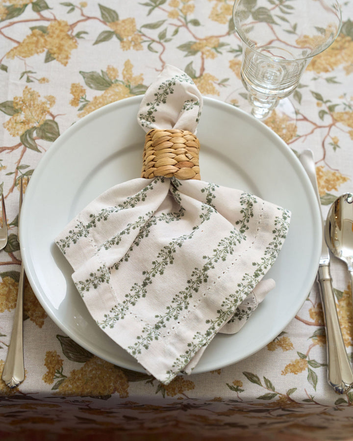 Set of four green floral stripe cotton napkins styled with classic dinnerware and coordinating linens for a layered, inviting table setting.