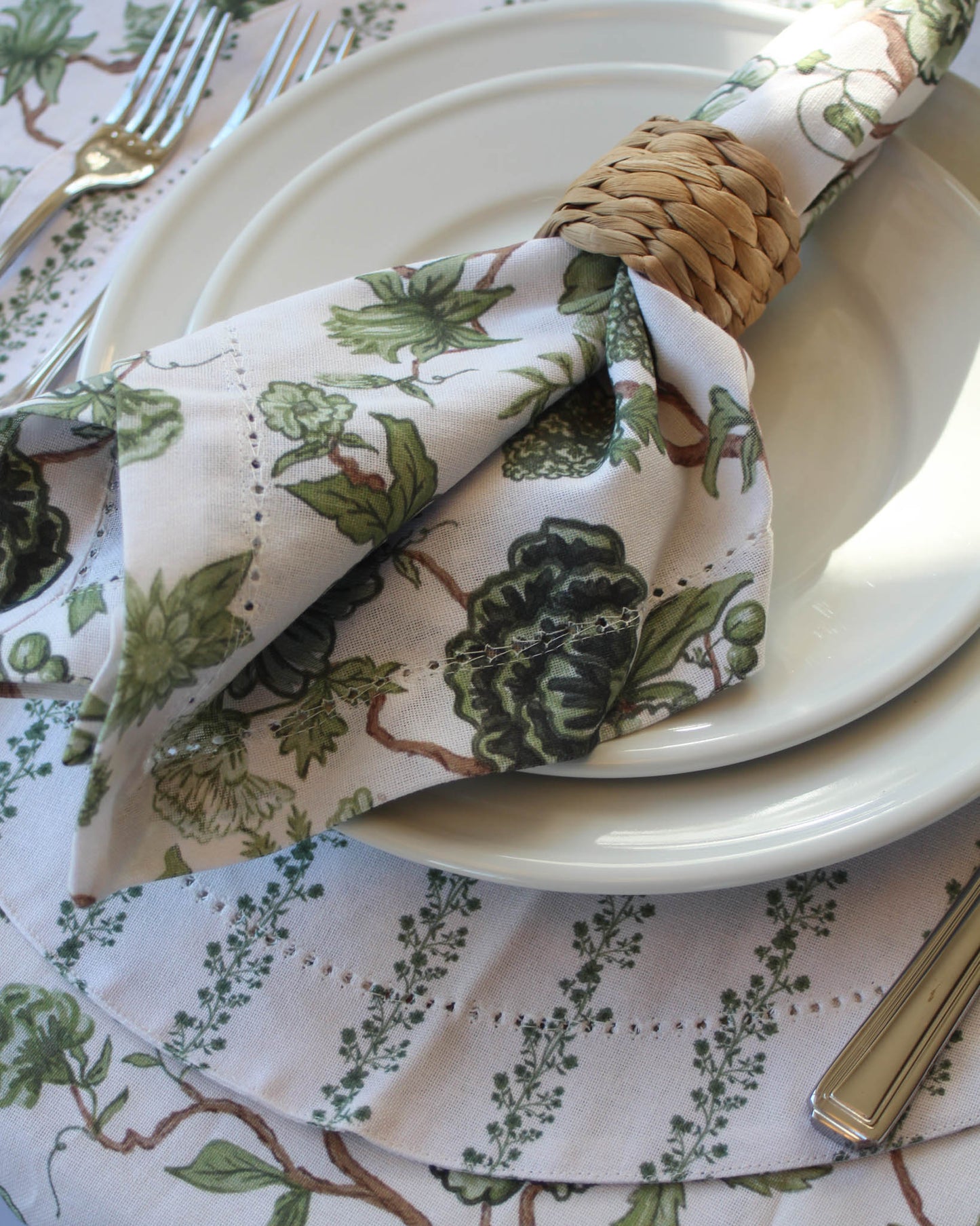 Napkin with green floral pattern on a white plate on a green floral tablecloth