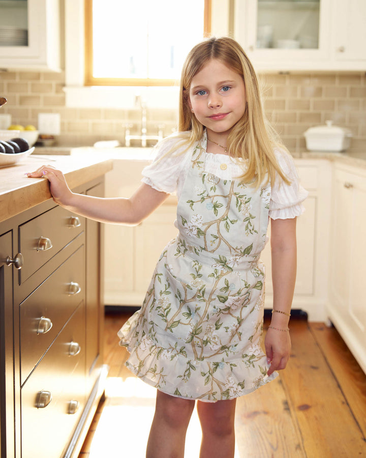 Camellia kids apron in 100% cotton with ruffle hem and pockets, perfect for baking, cooking, and creative play.