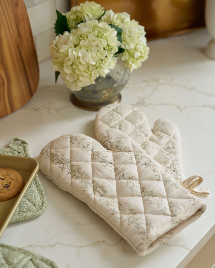 Hand-drawn floral stripe cotton oven mitt set with a soft cream background, moss green and pale yellow botanicals, heat-resistant lining, and quilted finish for everyday kitchens, seasonal cooking, bridal showers, housewarming gifts, holiday baking, and year-round display.