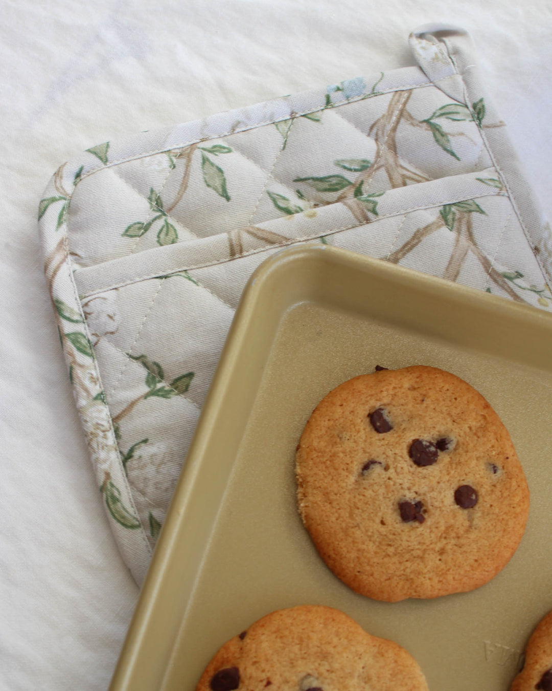 Spring-ready camellia cotton pot holder styled alongside coordinating kitchen linens.