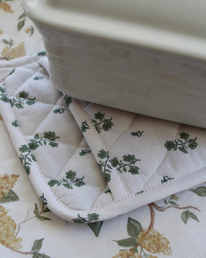 High-quality green floral bouquet print potholder set of 2, designed for the stylish country kitchen. These quilted hot pads are crafted from premium cotton with recycled cotton insulation to handle hot pans and trays safely. Each 8 inch woven potholder includes a loop for hanging storage. Ideal for grand millennial decor, they serve as the perfect floral hot pads or quilted trivets. Give the best gift for mom or a gift for her that combines beauty with utility for all baking.