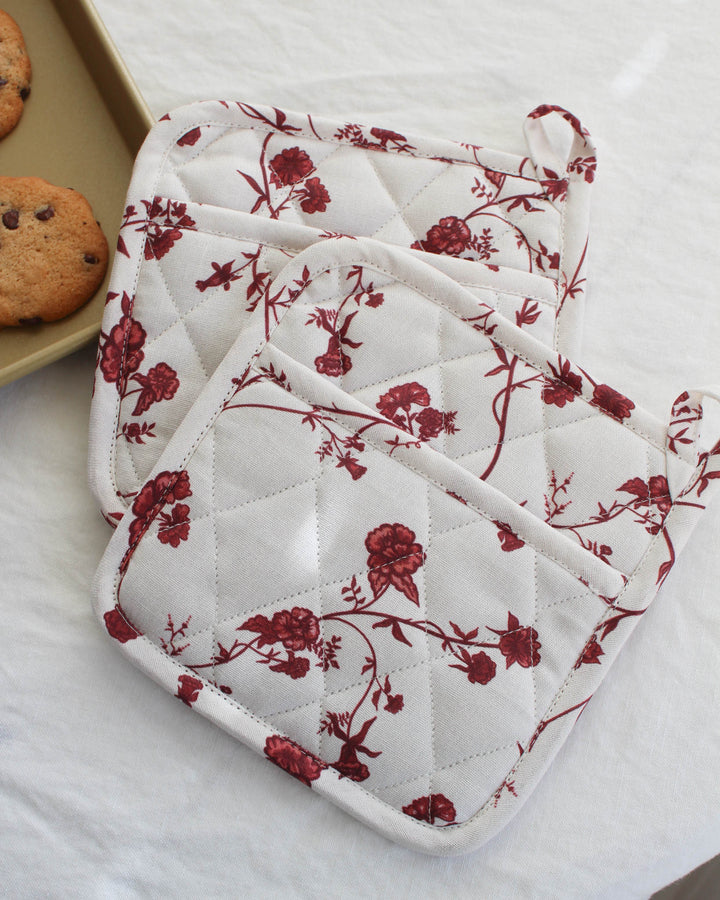 High-quality red floral potholder set of 2 featuring a timeless botanical design inspired by Charleston gardens. These quilted potholders for baking and cooking are crafted from premium cotton with thick insulation for safe handling of hot dishes and pans. Measuring 8 inches square, each woven potholder includes a convenient loop for hanging. Use them as quilted hot pads or trivets to protect surfaces while entertaining. A beautiful gift for mom, grandma, or a hostess under $50.