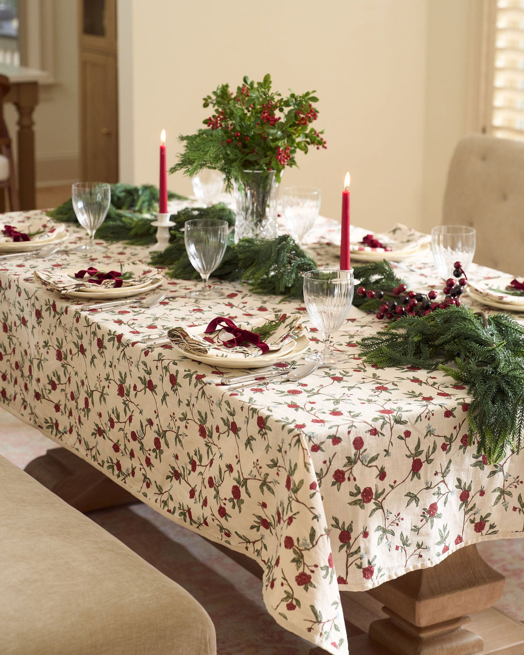 Classic Christmas table setting with red and green floral table linens, coordinating napkins, and elegant holiday place settings for festive entertaining.