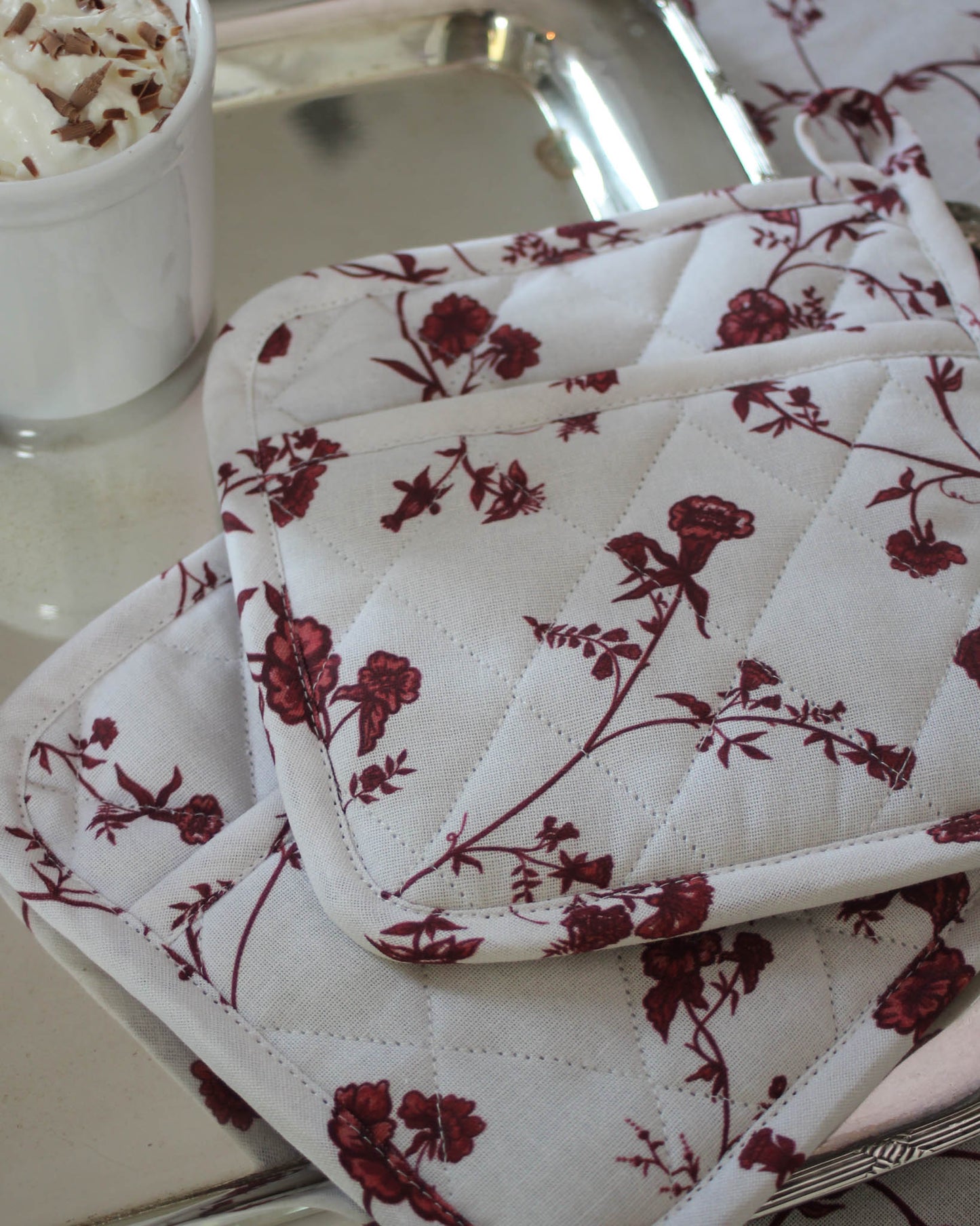 Red floral pot holders made from sustainable cotton, perfect for gifting to home cooks or bakers.