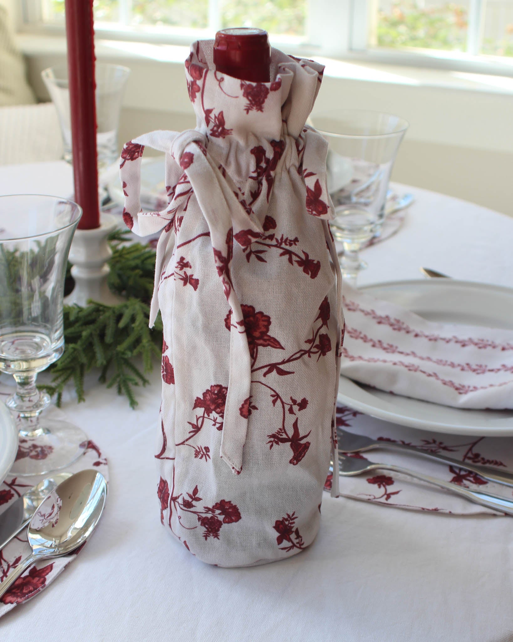 Reusable organic cotton wine bag featuring red florals and refined drawstring detailing.