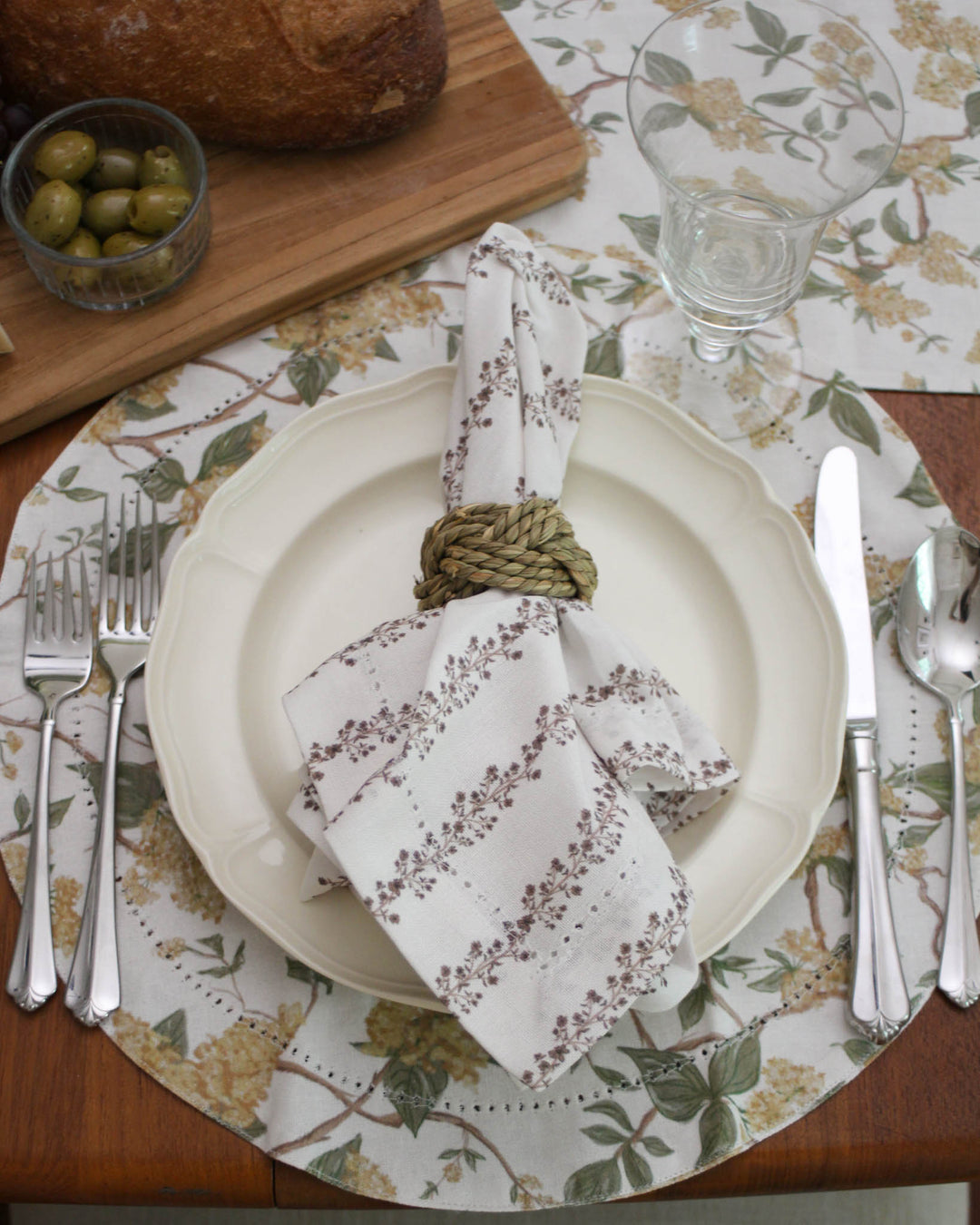 Achieve a timeless botanical look with these yellow floral round placemats. The intricate pattern of flowers and greenery creates a sophisticated atmosphere for a bridal shower or summer dinner. These cloth placemats are made from premium cotton with a classic hemstitched finish. As washable and reusable table linens, they provide both beauty and ease for your home. Use them to create a layered, French country aesthetic that feels curated, warm, and inviting for your guests.