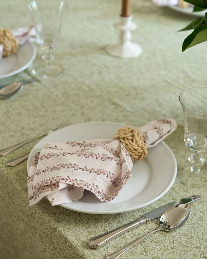 Neutral Thanksgiving table linens featuring a cream, brown, and sage green botanical tablecloth for an elegant autumn tablescape.