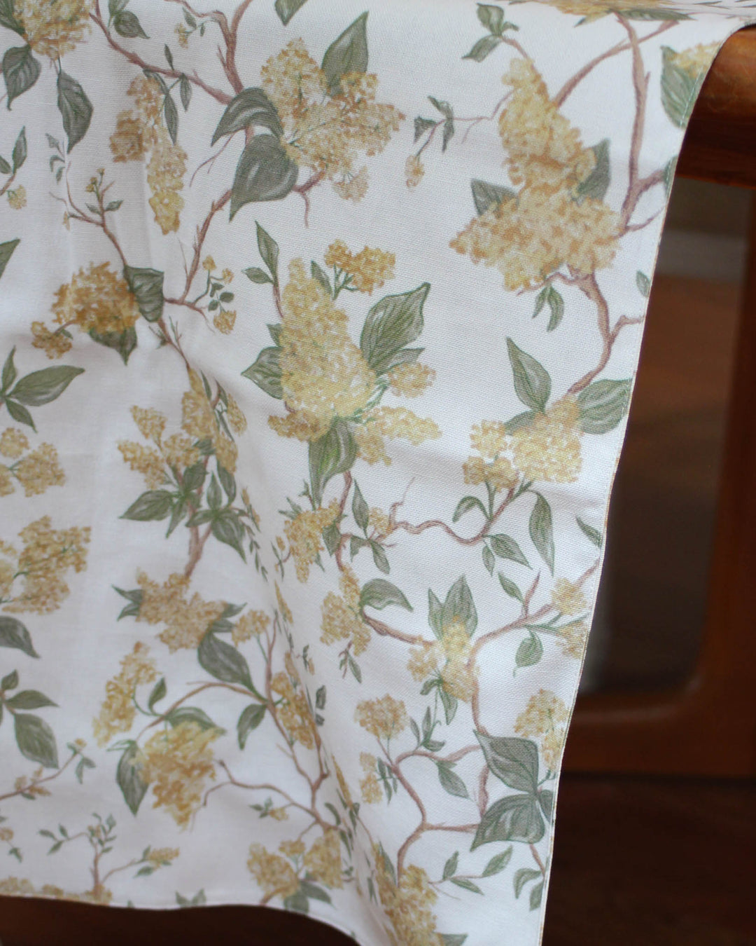 Embrace the grandmillennial and cottagecore aesthetic with this yellow floral table runner. Featuring a delicate hand-drawn botanical print, this 100% cotton runner brings a vintage charm to your dining room. Perfect for spring hosting, Easter Sunday, or a casual farmhouse breakfast. Available in extra-long 120-inch sizes for large family gatherings. The organic cotton fibers are soft and durable, offering an earthy, high-quality feel that complements traditional and modern homes.