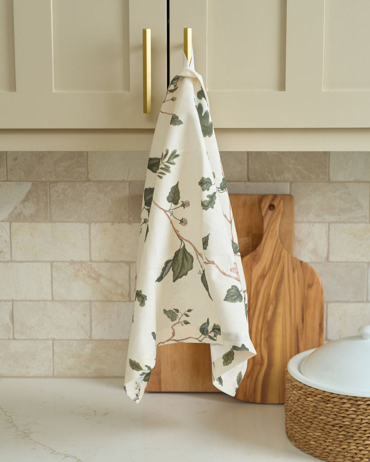 Arbor neutral woodland botanical cotton tea towel with green winter foliage, styled for Christmas baking and holiday kitchen décor.