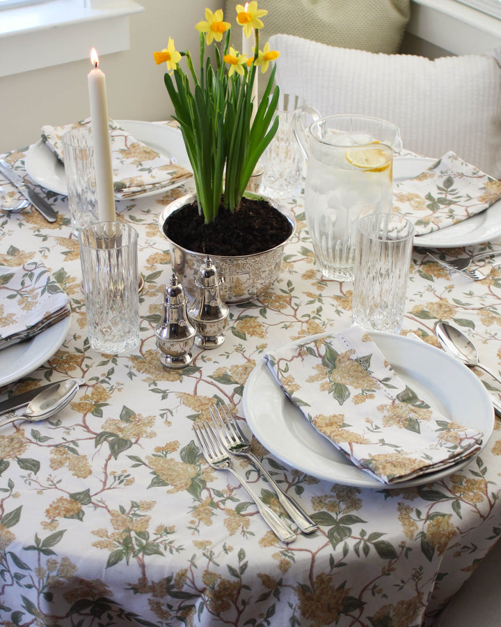 Yellow floral cotton tablecloth styled on a bridal shower table with fresh flowers and layered place settings.