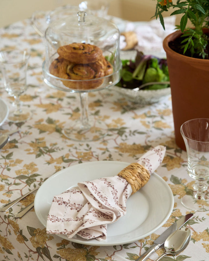 Elegant yellow floral tablecloth in premium cotton, styled with layered table linens and classic place settings for a warm fall gathering or Thanksgiving dinner.