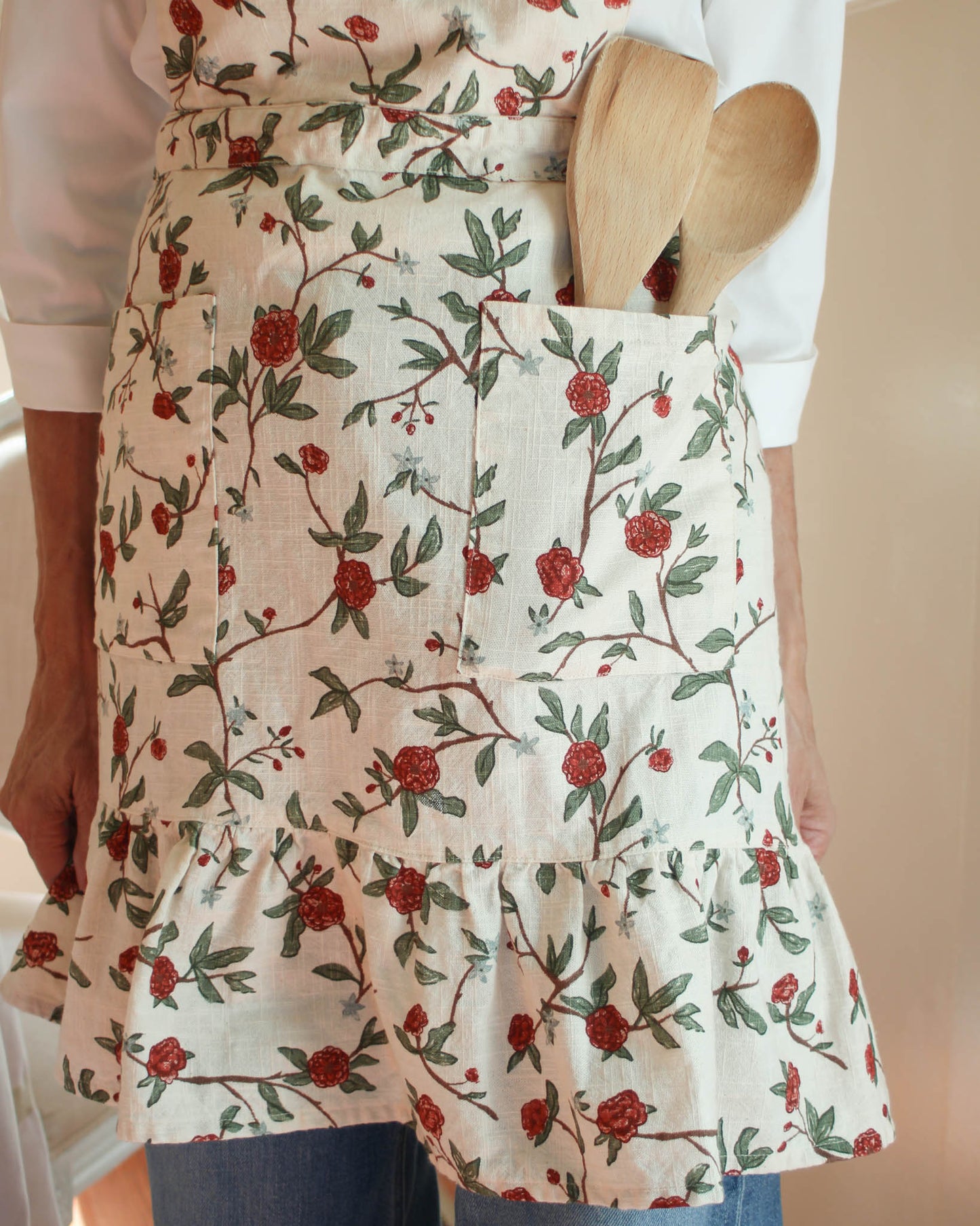 A charming vintage-inspired red floral apron dress with pockets, featuring a beautiful and intricate floral pattern. Ideal for adding a touch of elegance and functionality to your kitchen, this apron combines style and practicality