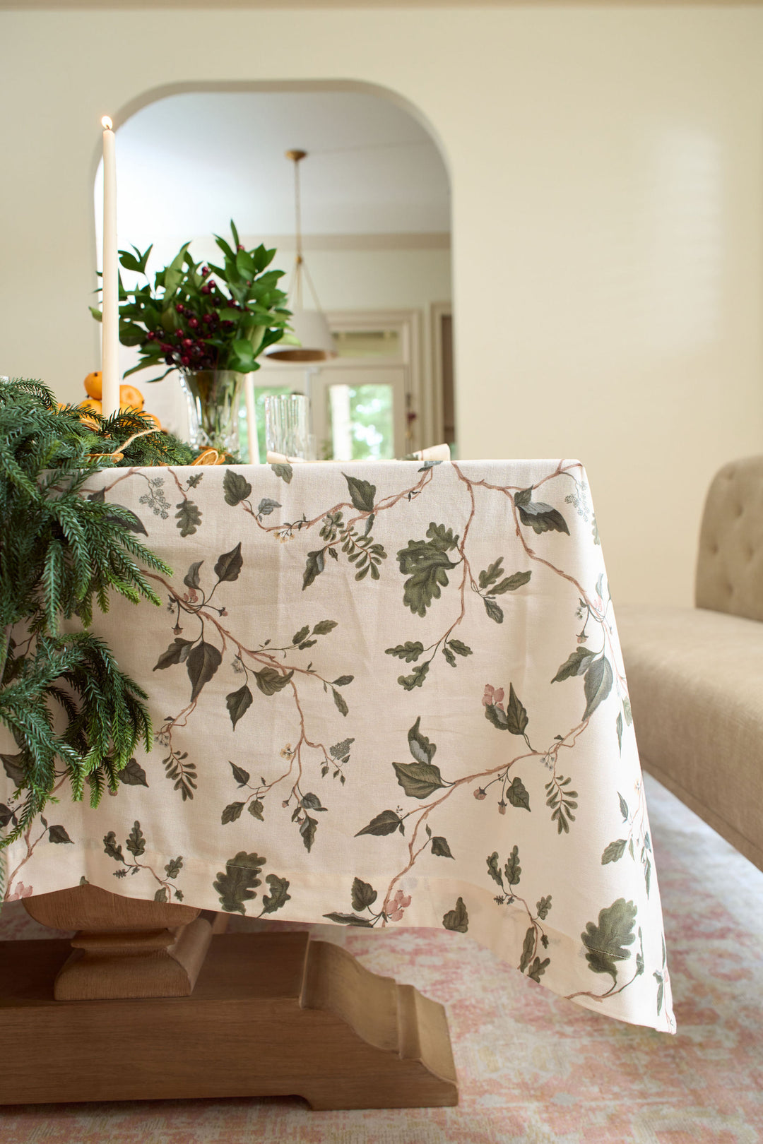 Botanical holiday table styled with an English countryside floral tablecloth, oak garden motifs, winter greenery, and elegant crystal glassware.