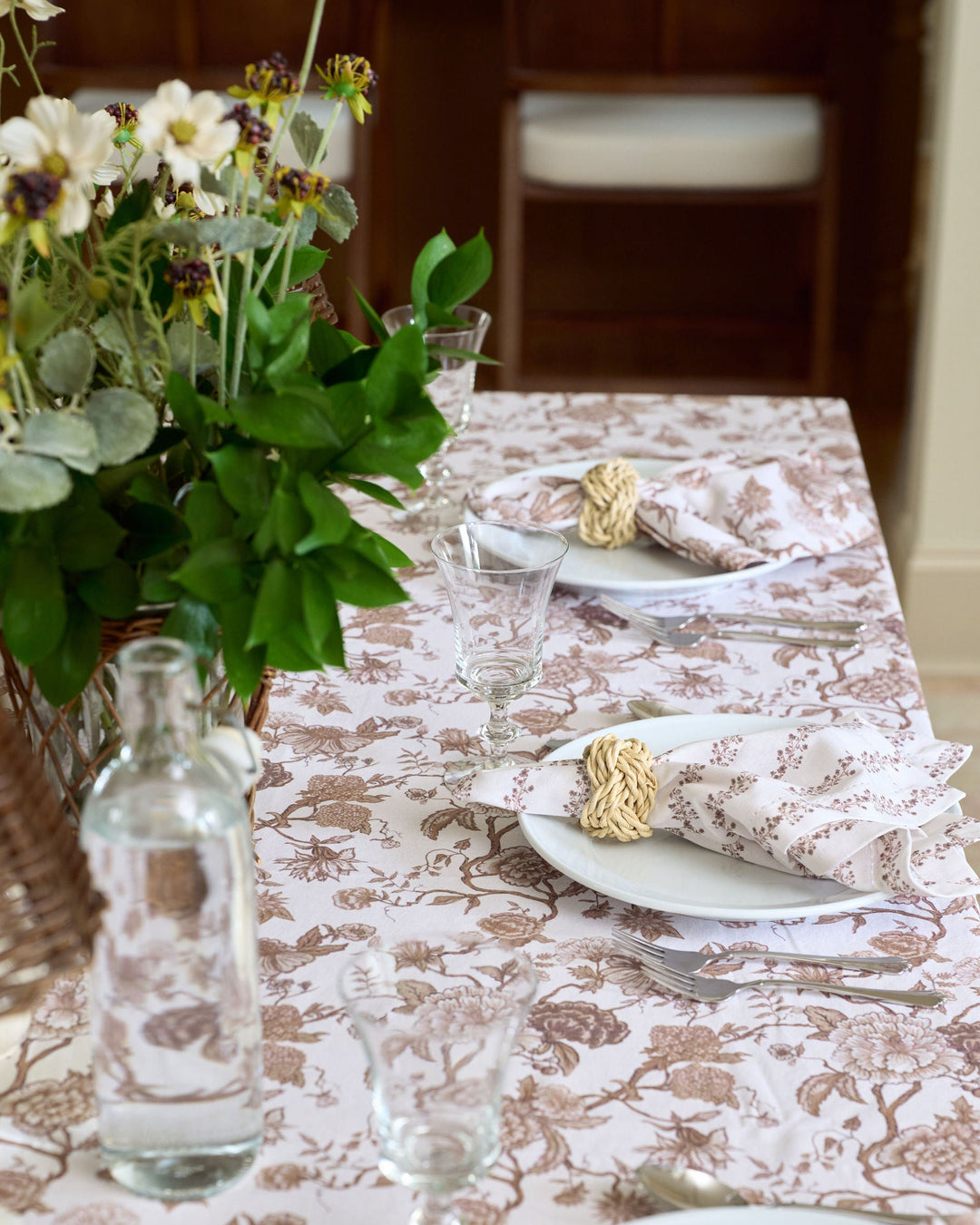 Brown floral napkins and a coordinating Thanksgiving tablecloth create a layered autumn tablescape with rich chocolate tones, classic pattern, and an inviting look for family dinners and seasonal entertaining.