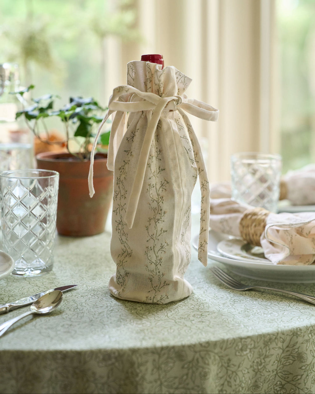 Reusable Meadow floral stripe cotton wine bag with drawstring closure, styled as a hostess gift for wine bottles, housewarmings, dinner parties, Thanksgiving gatherings, Christmas gifting, holiday entertaining, and homemade treats.