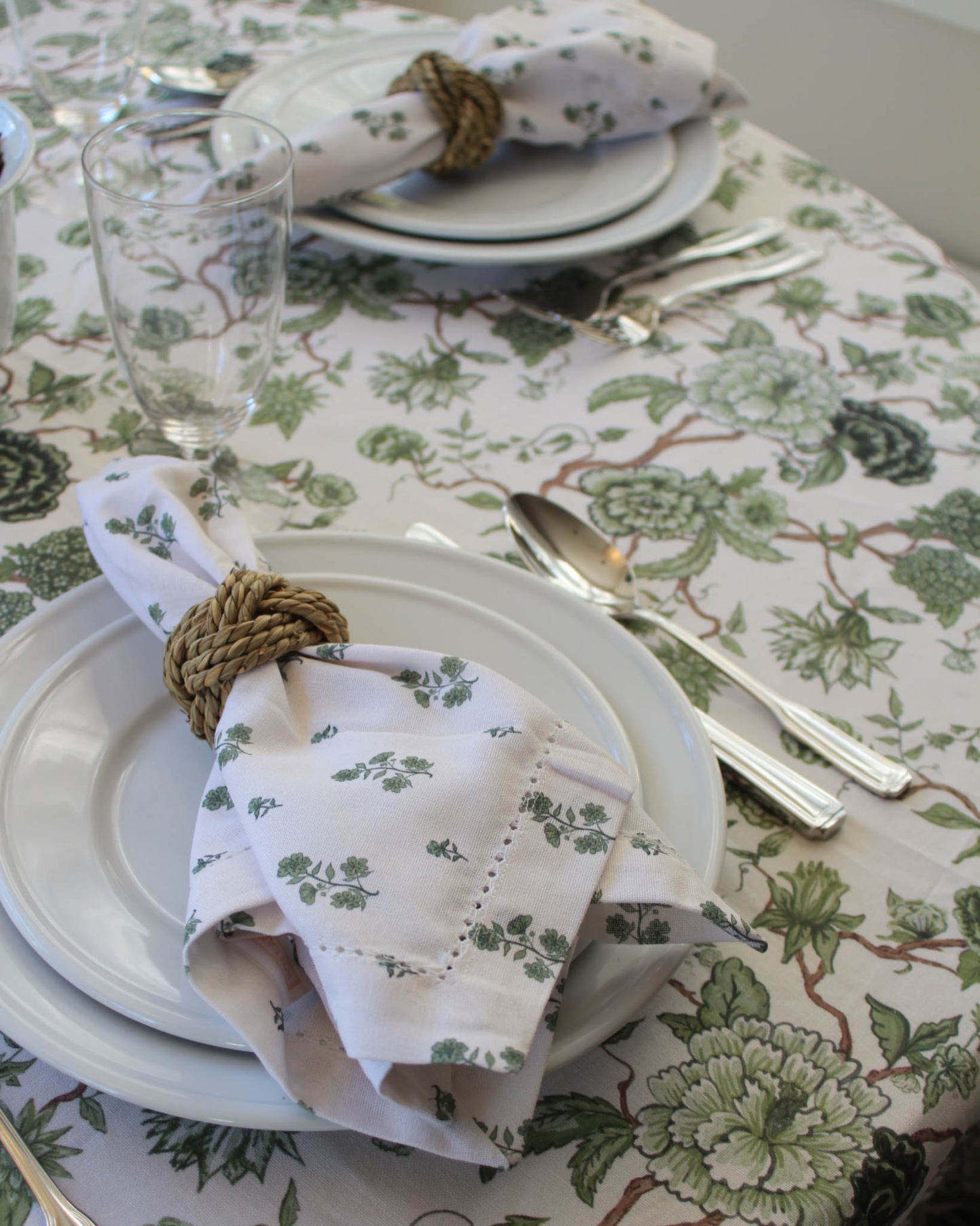 Table setting with green floral napkins and cutlery on a green floral tablecloth