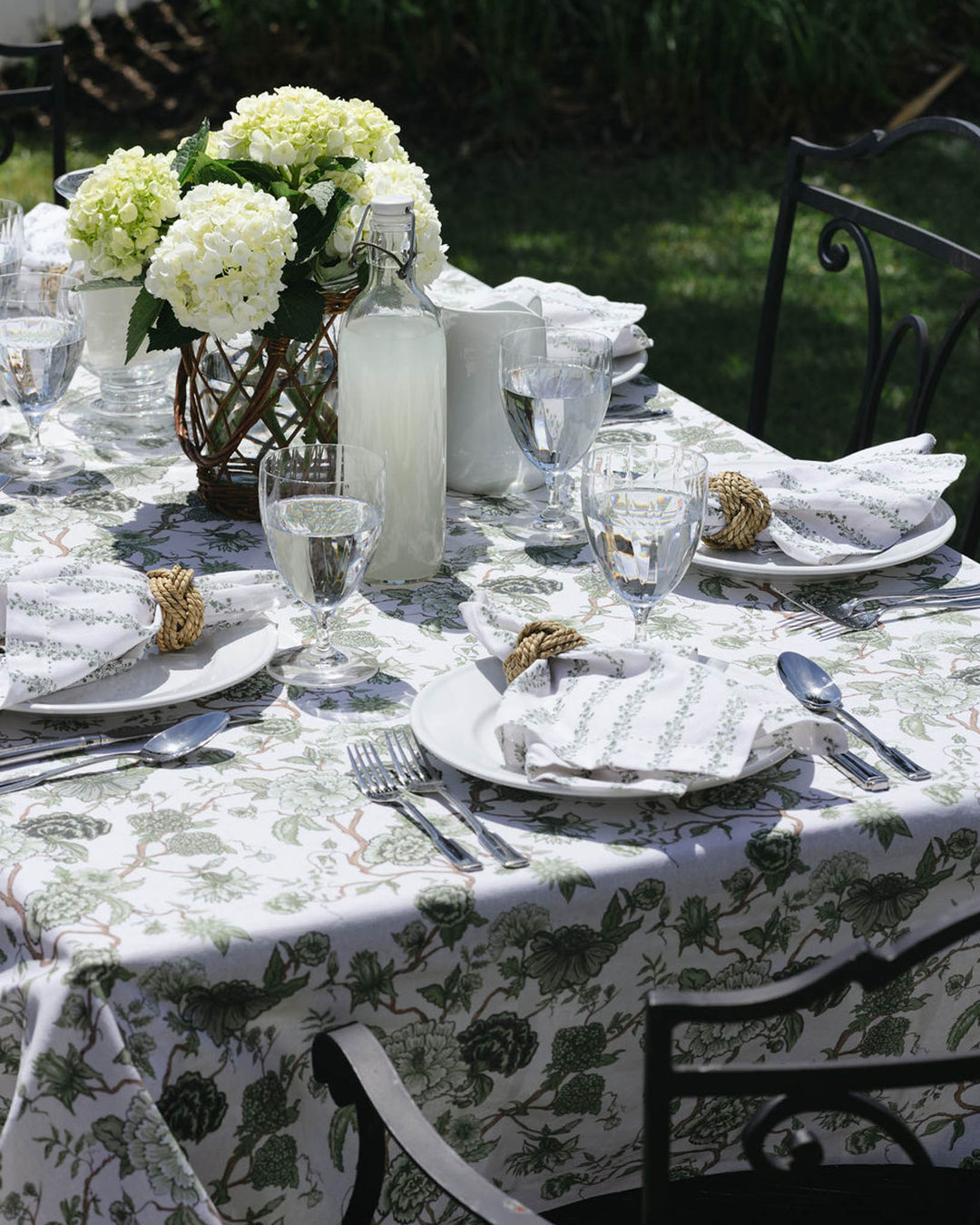 Florence green floral tablecloth in 100% cotton, hand-drawn print styled on a summer table with fresh garden-inspired decor.