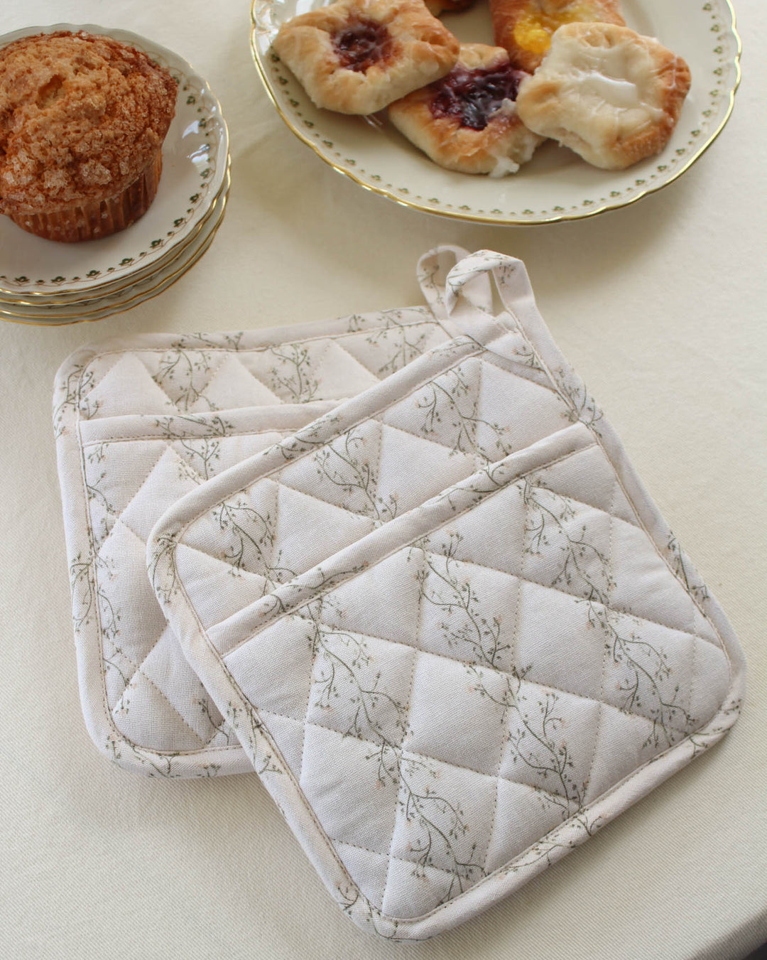 Quilted cotton pot holder featuring a hand-drawn floral print, designed for safely handling hot cookware while adding timeless style to the kitchen.