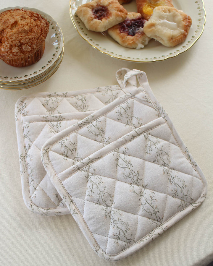 Quilted cotton pot holder featuring a hand-drawn floral print, designed for safely handling hot cookware while adding timeless style to the kitchen.