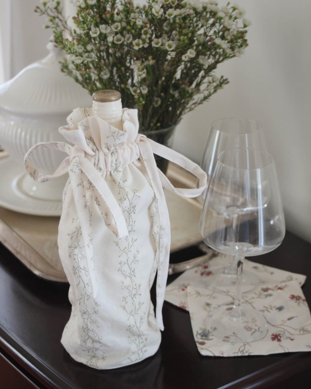 Cotton wine bag featuring a hand-drawn floral print and drawstring closure, designed for gifting wine at dinners, weddings, and special occasions.