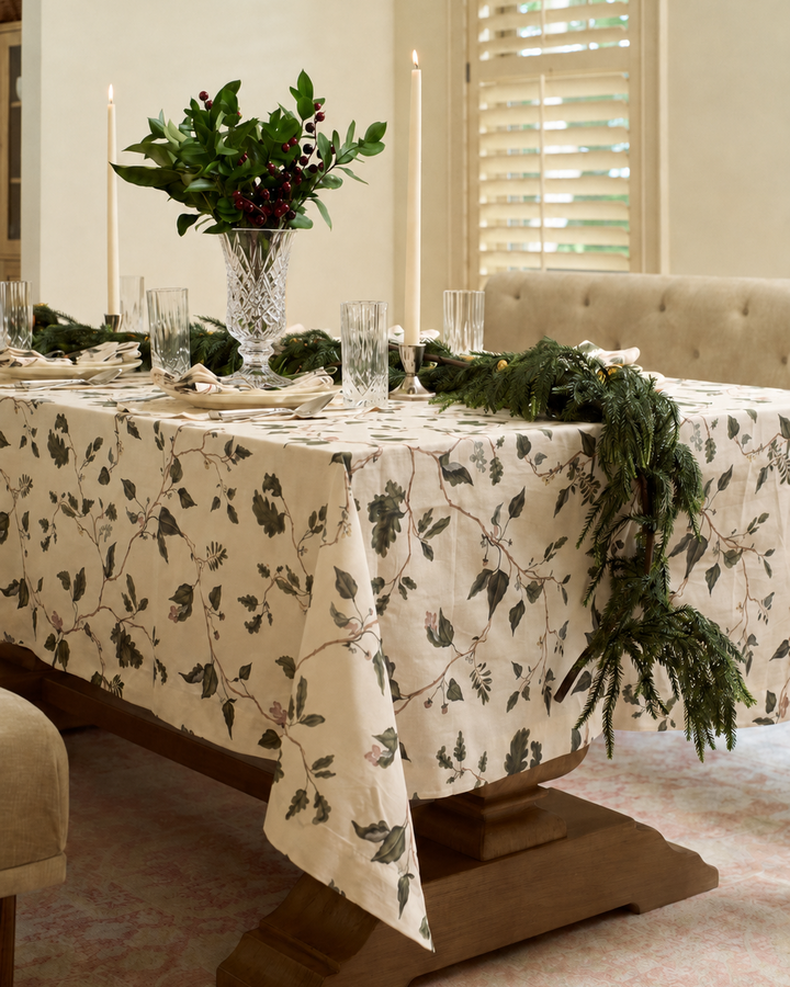English countryside botanical tablecloth styled for Christmas with neutral holiday table linens, oak garden foliage, taper candles, and cut crystal.