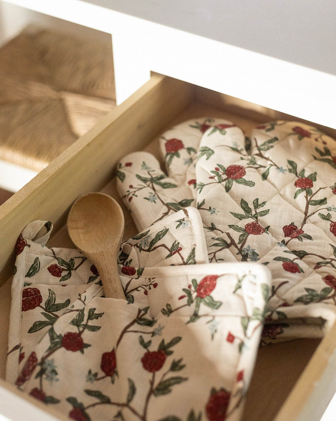 Intricate diamond-stitched oven mitts featuring a hand-drawn red and green botanical print. Every detail of these 100% organic cotton gloves reflects a passion for quality and art. The heat-resistant fill provides safe handling of hot cookware, making them as practical as they are beautiful. Measuring 7" x 13.5", these mitts offer an elegant layer of protection for your hands. A stunning addition to a curated collection of floral kitchen linens and accessories.