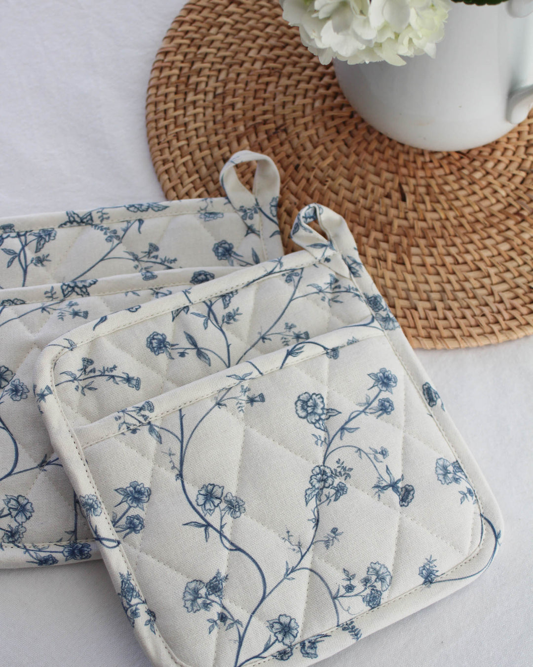 Garden Vine pot holders in blue and white cotton with quilted texture and heat protection, styled for a coastal-inspired kitchen.