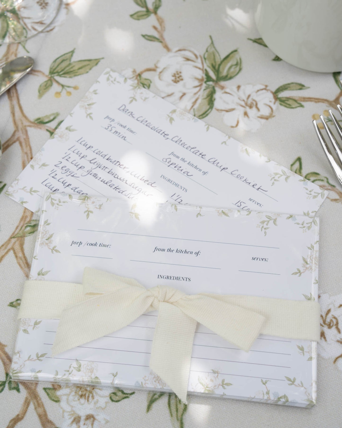 A set of recipe cards with a floral pattern, tied with a ribbon.