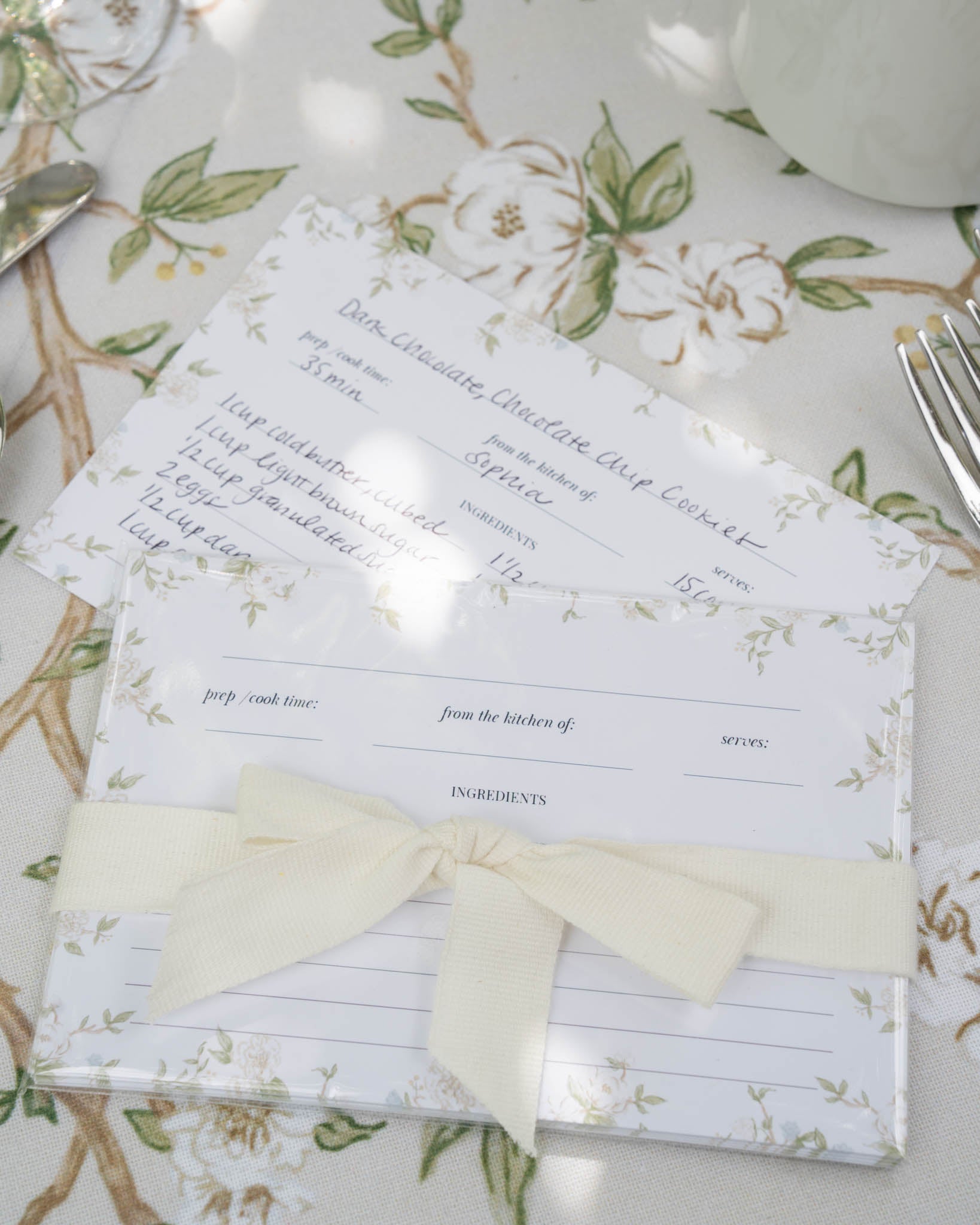 A set of recipe cards with a floral pattern, tied with a ribbon.