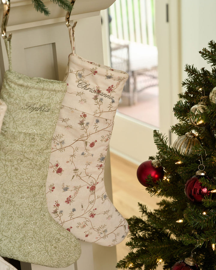 Personalized floral Christmas stocking featuring an antique-inspired botanical print, embroidered name, hanging loop, and traditional Christmas mantel decoration.