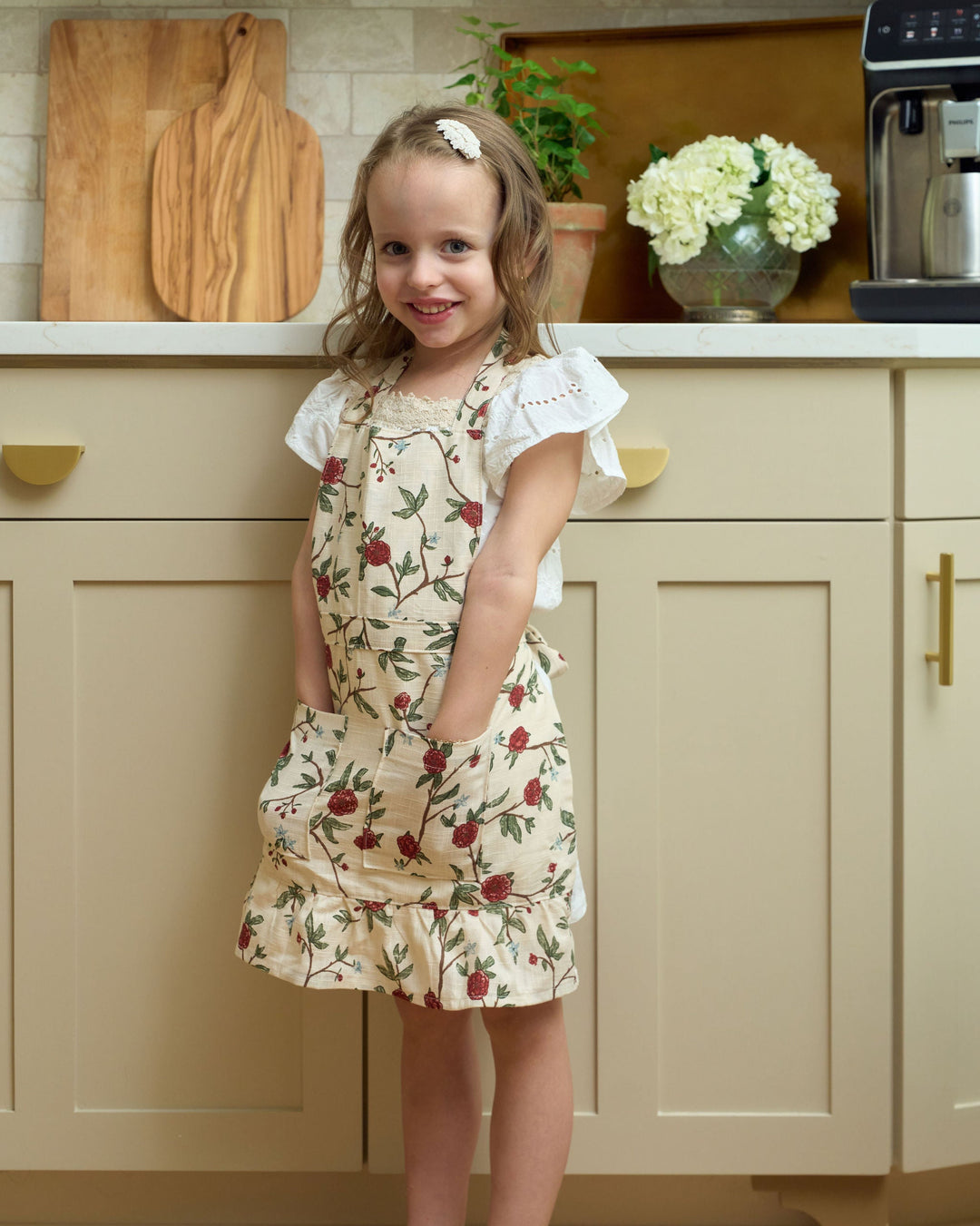 Little red and green floral Christmas apron for girls, made from premium cotton for holiday baking and festive kitchen fun. Designed for ages 4–7 with a ruffle hem, front pockets, and adjustable waist ties. Pair it with the matching adult apron for a sweet mommy-and-me Christmas baking set. Add an embroidered monogram for a personalized holiday gift.